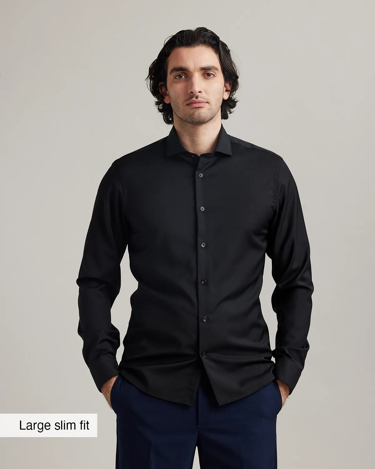 Man wearing a black merinowool formal shirt with 'Large slim fit' label on a gray background.