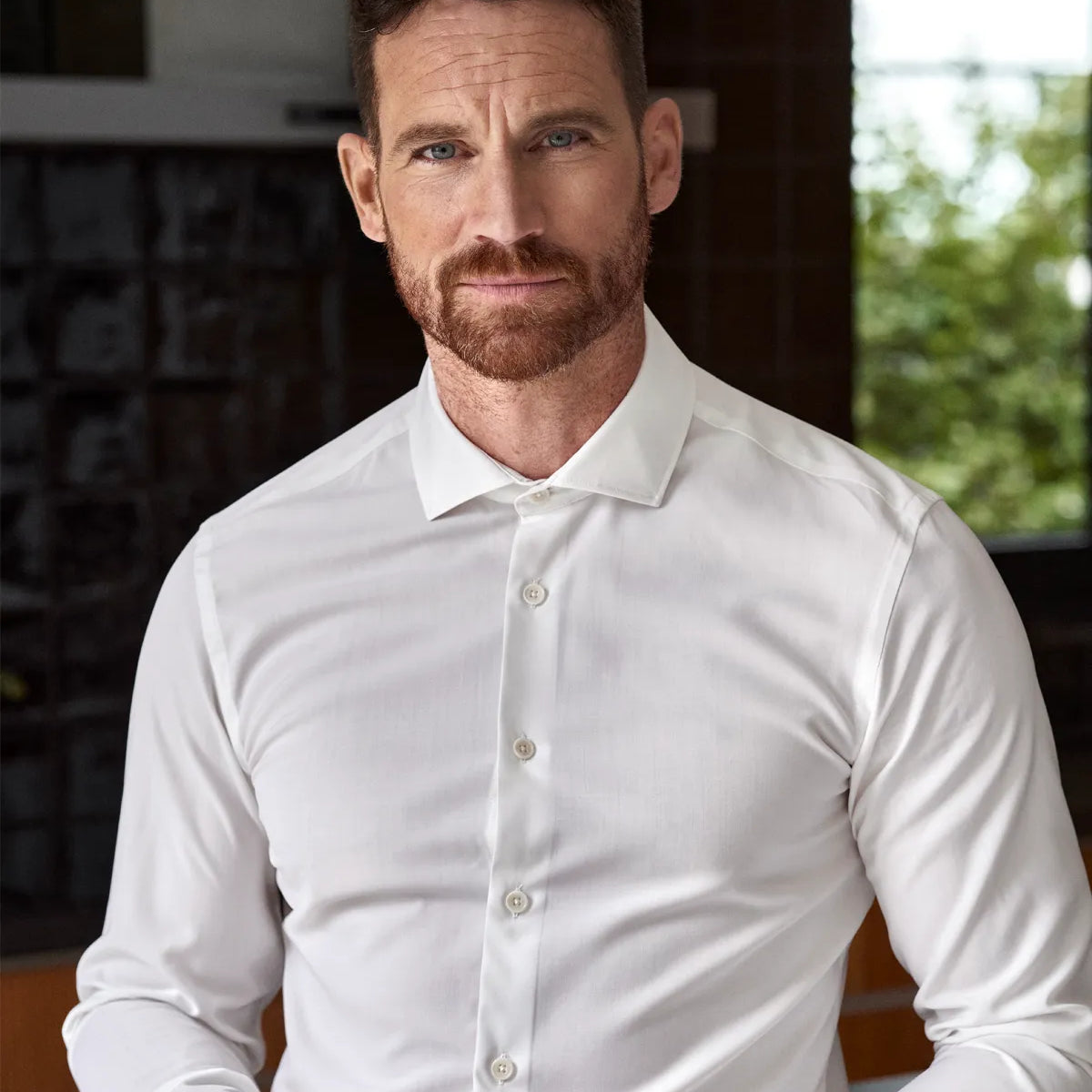 Man in a white merino wool formal shirt from Wolk shirt holding a coffee cup indoors