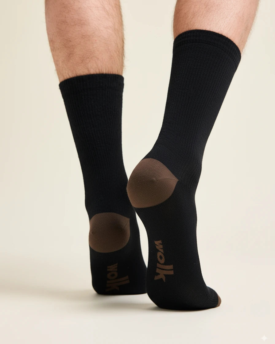 Black merino wool socks with brown accents and Wolk logo worn by a person on a beige background