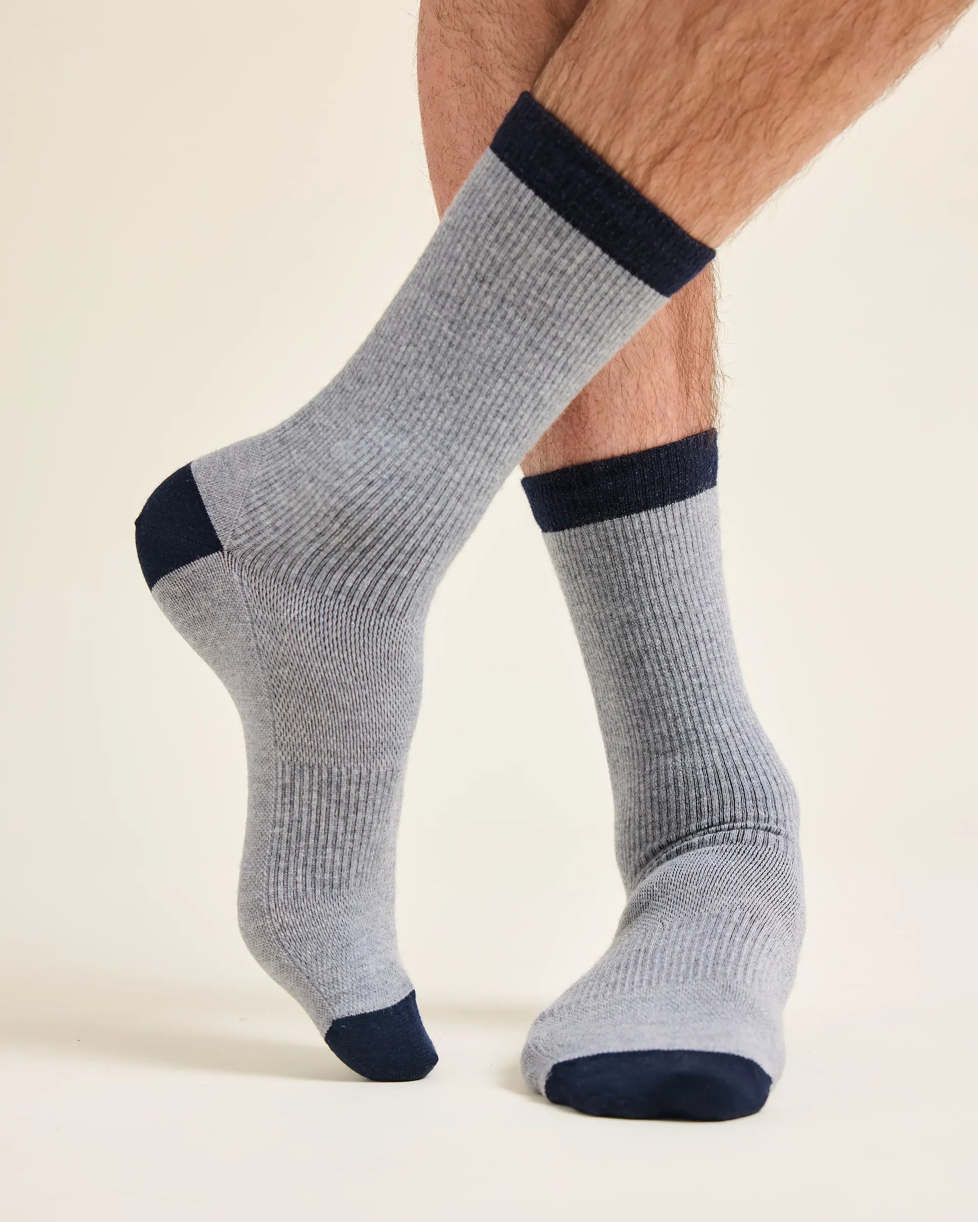 Gray merino wool socks with navy accents worn by a man with ventilation and rib texture