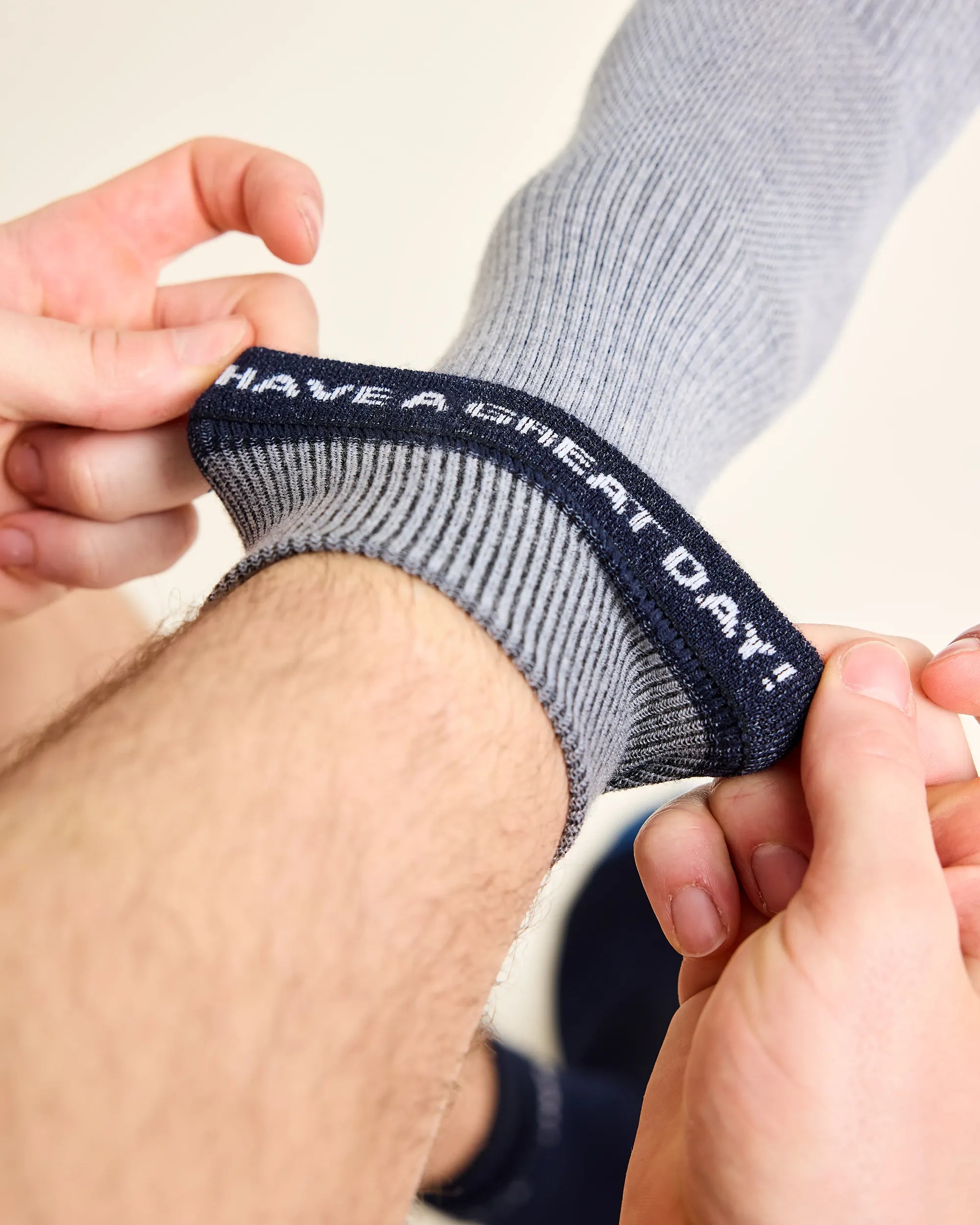 Man wears a merino wool sock with rib texture in grey with at the inside a text