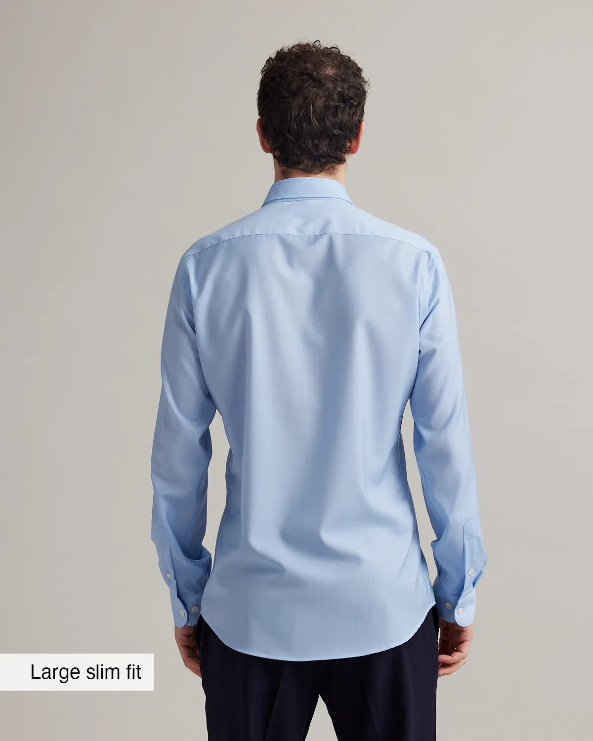 back view of a man wearing a light blue shirt with text 'Large slim fit' on a gray background