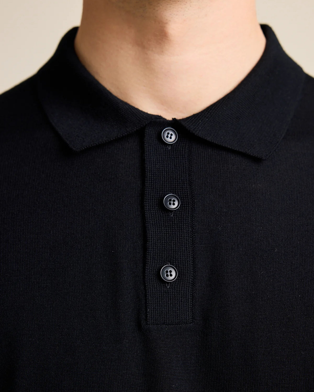 Detail of the collar on the black men's merino polo from the European brand Wolk.