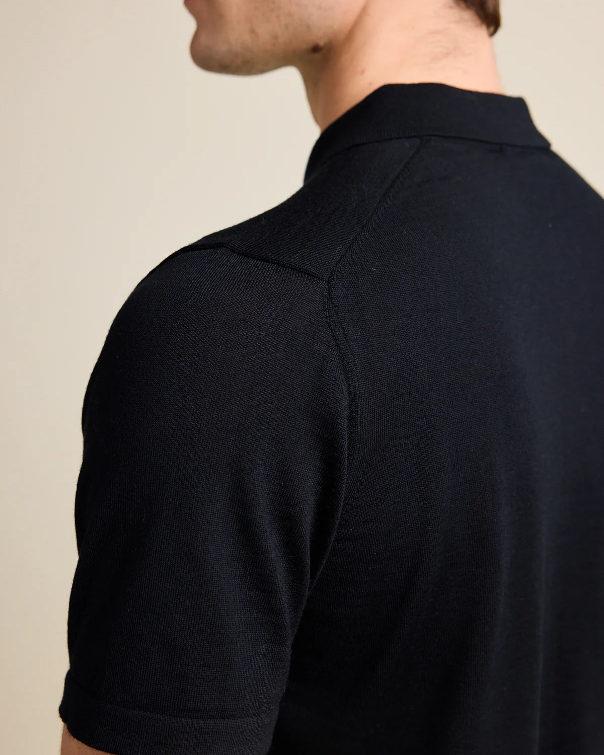 Shoulder detail of a men's black merino wool Polo shirt from Wolk, emphasizing the luxurious Cashwool knit.