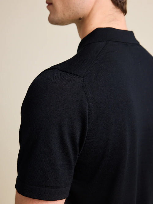 Détail d'épaule d'un polo en merino noir pour homme de Wolk, mettant en avant le luxueux tricot Cashwool.