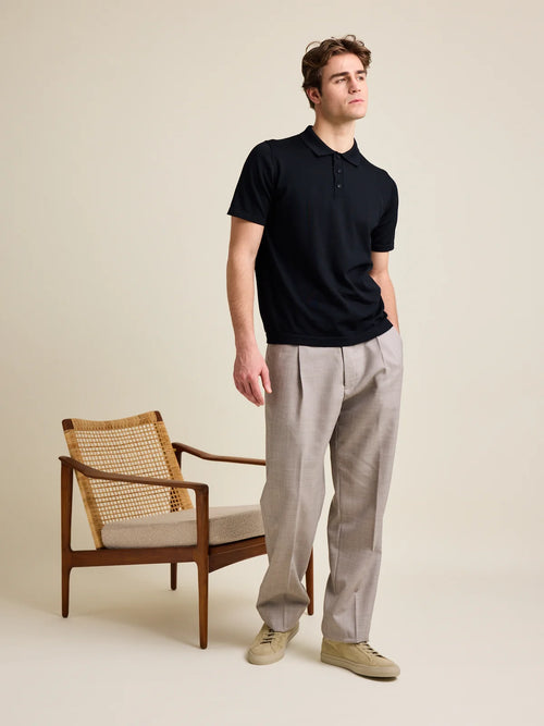 Photo en studio d'un polo noir en laine mérinos pour homme de Wolk, mettant en valeur sa surface douce en laine Cashwool.