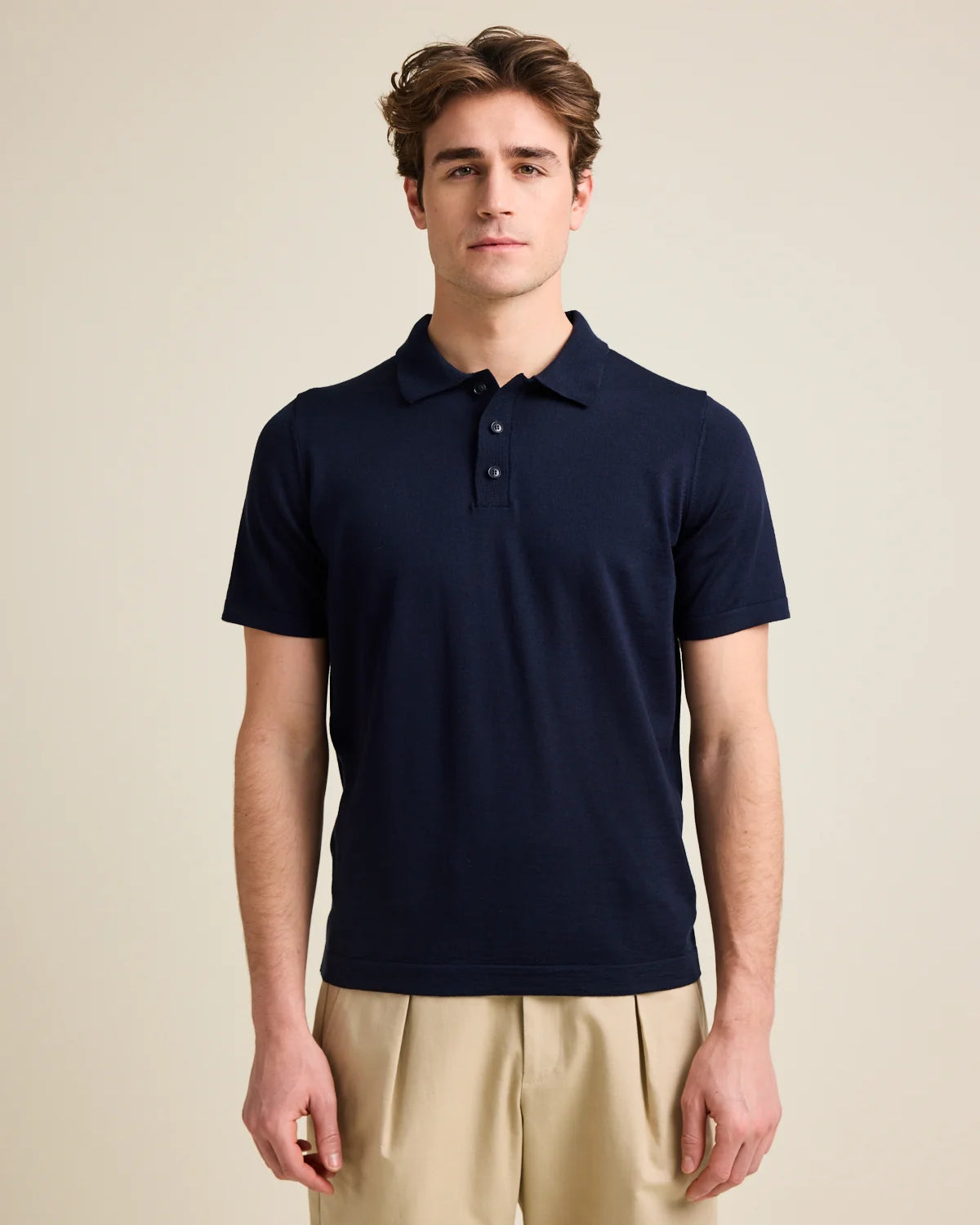 Man wears a short sleeves merino wool polo, knitted with zegna baruffa extra fine merino cashwool in dark navy color from the European brand Wolk.