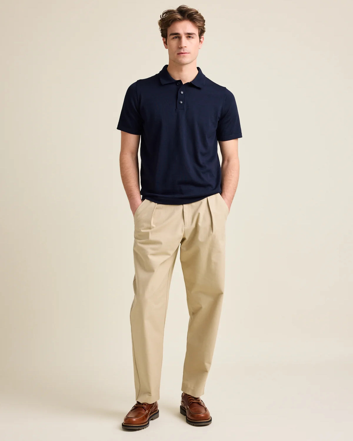 Man wears short sleeve merino wool polo from Wolk in dark navy blue color with 3 buttons and regular collar.