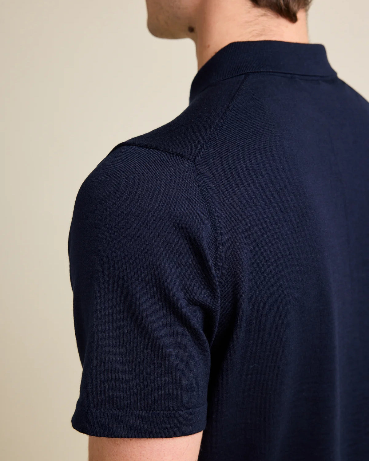 Shoulder detail of a men's darknavy blue merino wool Polo shirt from Wolk, emphasizing fine knitting and Cashwool quality.