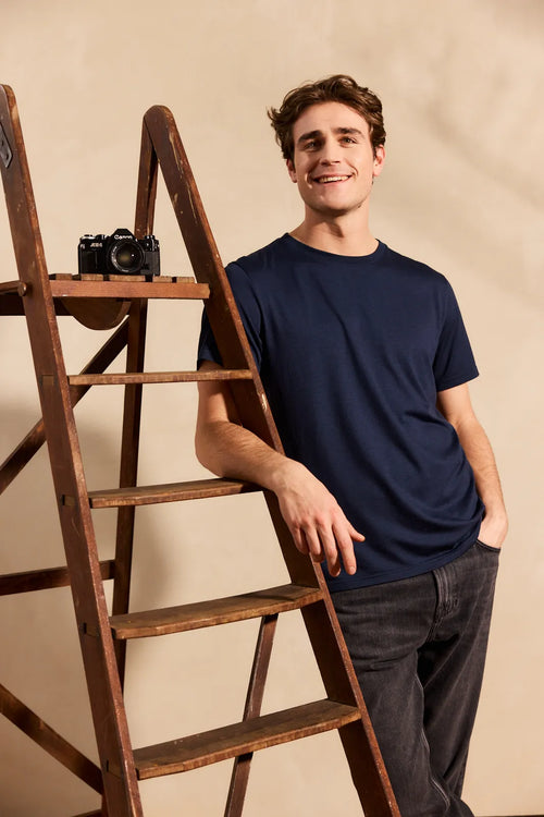 Lifestyle shot of a men's dark navy blue merino wool T-shirt from Wolk, highlighting its crew neck and soft texture.