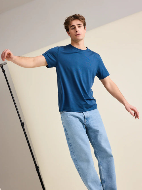 Front view of a male model wearing a denim blue colored merino wool T-shirt from the Wolk brand.