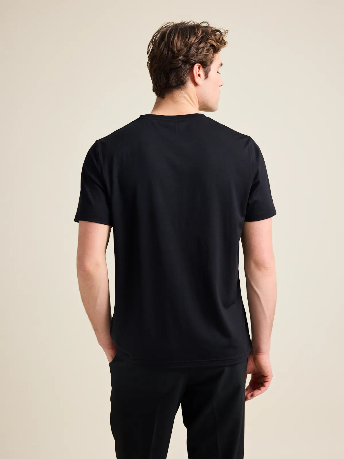 Back view of a male model wearing a black merino T-shirt from the Wolk brand.