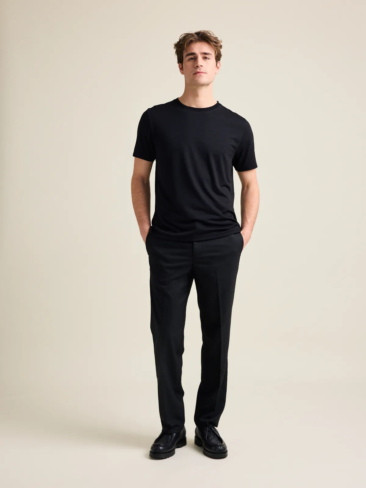 Studio shot of a men's black merino wool T-shirt from Wolk, displaying the front profile and sleek design with crew neck.
