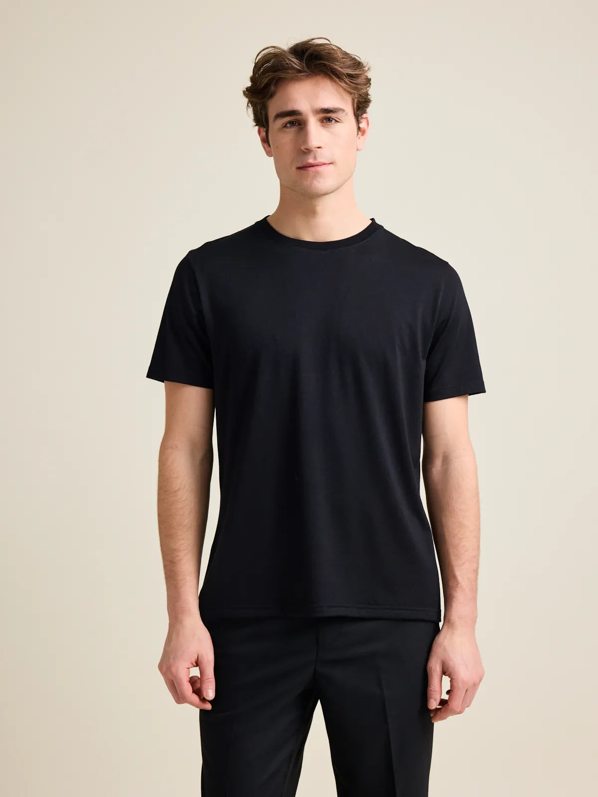 Men's merino wool T-shirt in black from Wolk in a studio setting, showcasing crew-neck and short sleeves design