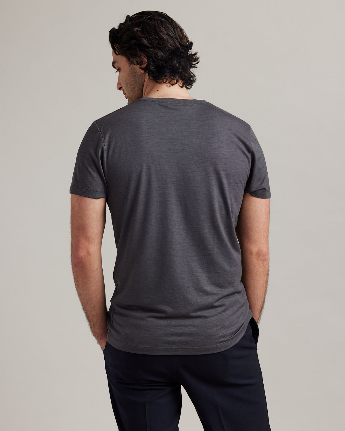 Studio shot of the back of a men's merino wool T-shirt in dark grey, designed by Wolk.