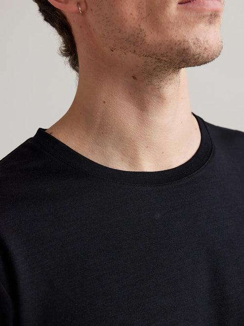 Detail of the crew neck on Wolk's black merino wool T-shirt for men, highlighting premium fabric.