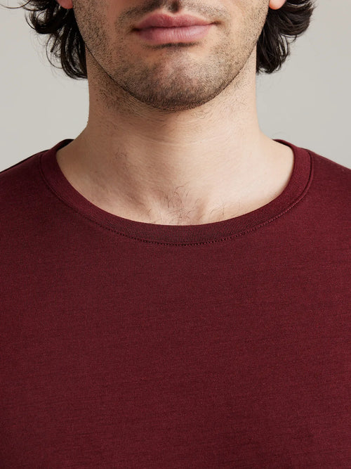 Close up of the crew-neck collar from a men’s merino wool T-shirt in burgundy from the brand Wolk.