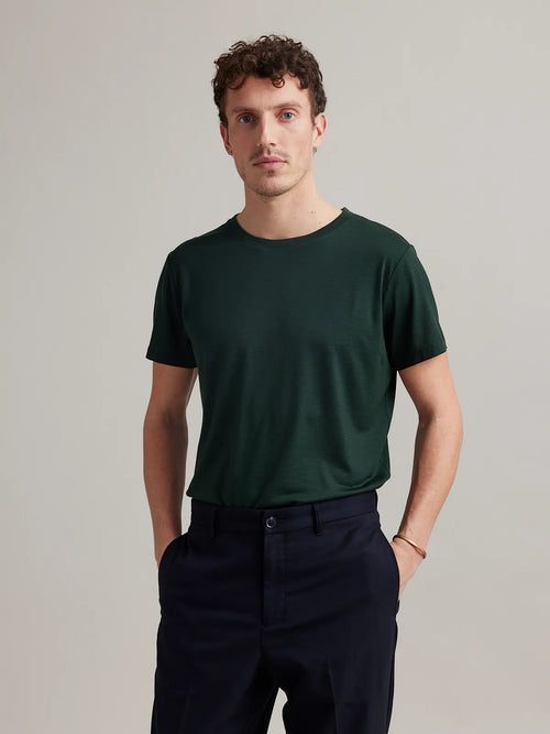 Studio shot of a men's merino wool T-shirt in dark green, designed by Wolk.