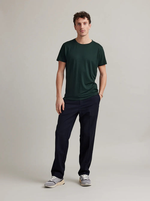 Man wears dark green merino wool T-shirt with crew neck and short sleeves from Wolk.