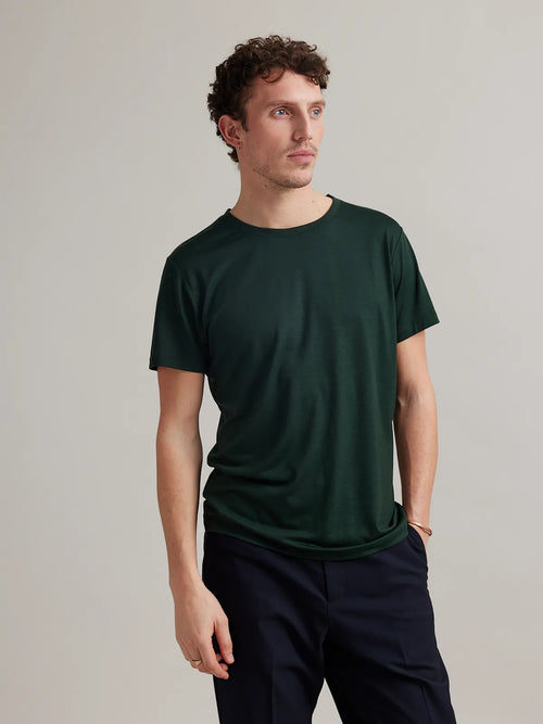 Wolk's dark green men's merino wool T-shirt in a studio setting, showcasing crew-neck design.