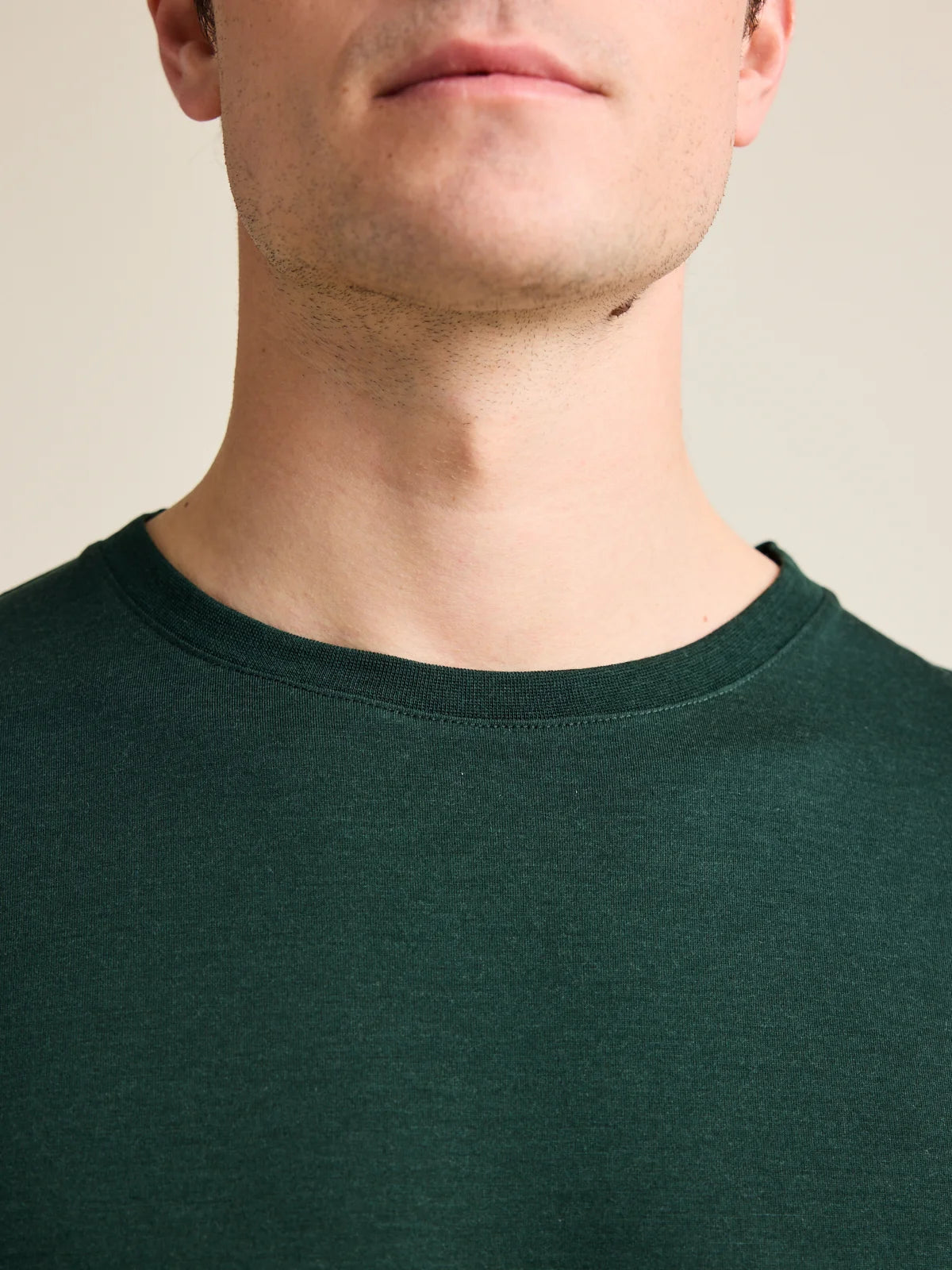 Close-up view of the collar of a men's dark green merino wool T-shirt by Wolk, showcasing European craftsmanship.