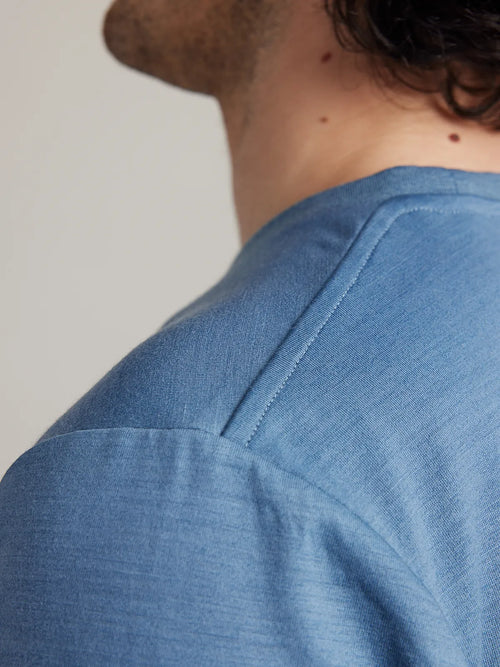 Close-up of the shoulder seam on Wolk’s light blue (stone blue) merino wool T-shirt for men.