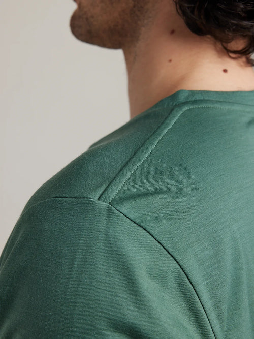 Close-up of the shoulder seam on Wolk’s pine green merino wool T-shirt for men.