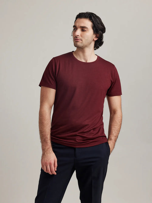 Studio shot of a men's burgundy merino wool T-shirt from Wolk, highlighting its crew neck and soft texture.
