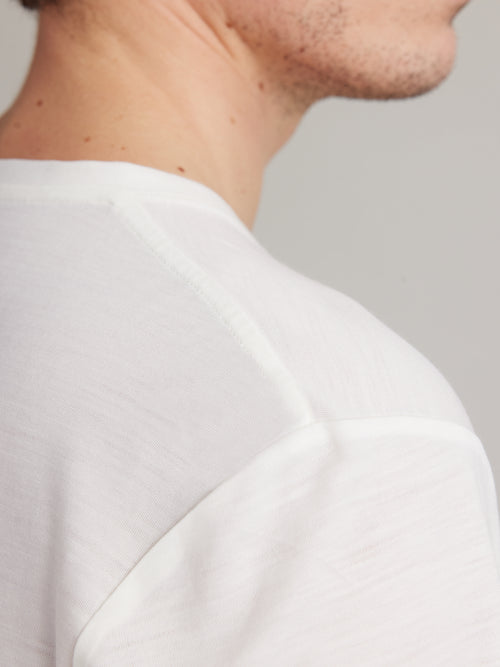 Shoulder detail of a men's white merino wool T-shirt from Wolk, emphasizing fine stitching and quality.