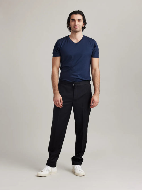 Man wears navy merino wool T-shirt with V neck and short sleeves from Wolk.