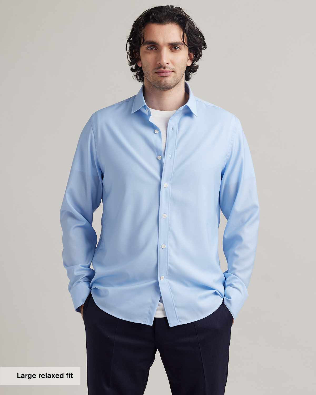 man wears light blue merino wool shirt with white merino T-shirt underneath on navy blue pants.