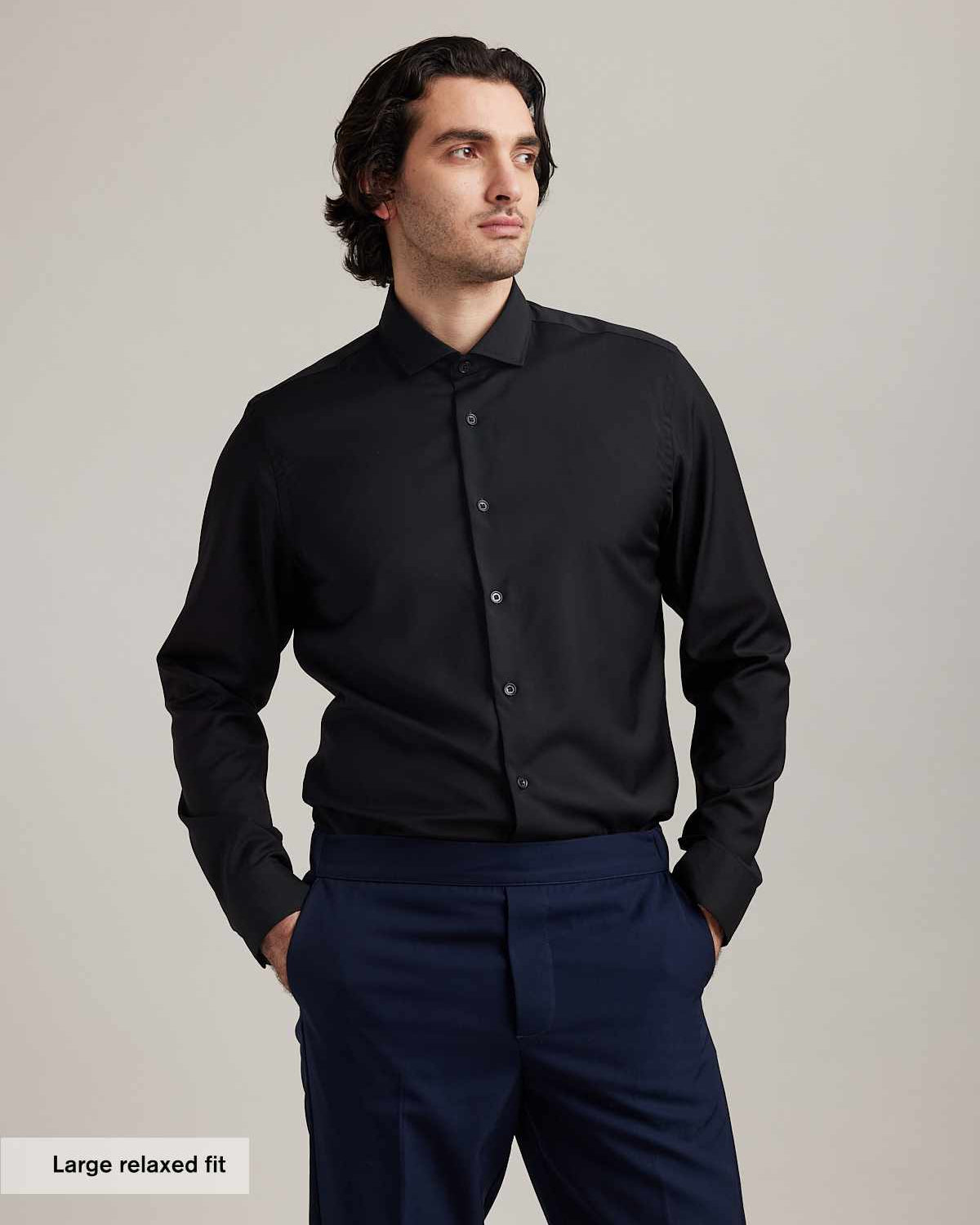 Man wears black merino wool formal shirt from Wolk with spread collar and long sleeves in relaxed fit
