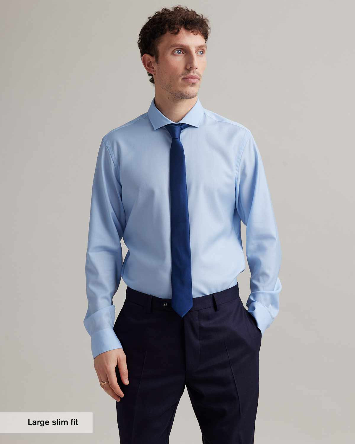 Man wears long sleeve woven shirt in merino wool light blue color and spread collar with tie