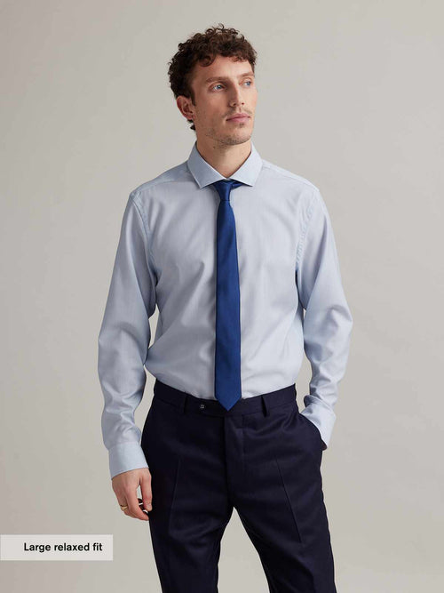 man wearing light blue merino shirt with spread collar and blue tie in relaxed fit