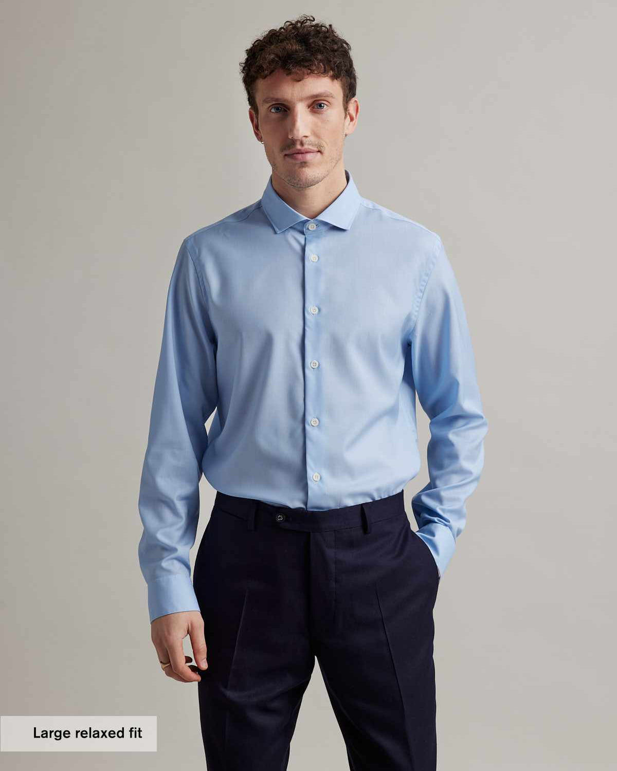 Man wears a light blue merino wool shirt with spread collar and white buttons in relaxed fit from Wolk