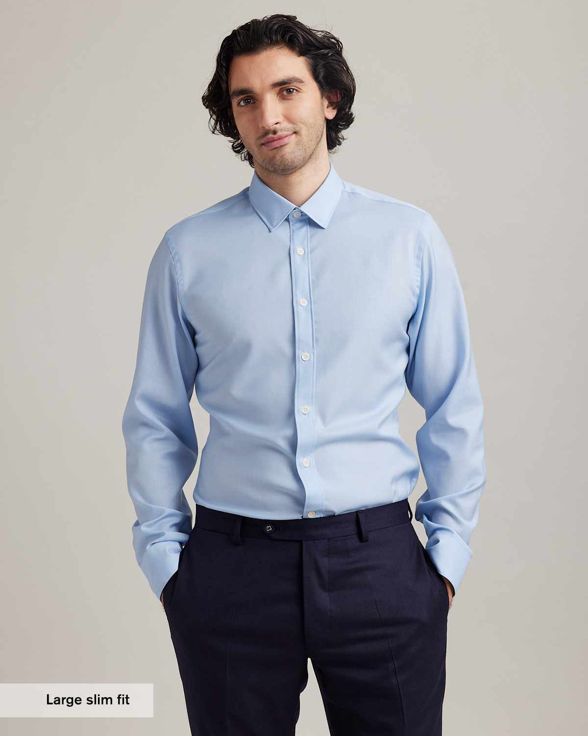 Man wears a light blue merino wool shirt from Wolk with classic collar white buttons and long sleeves