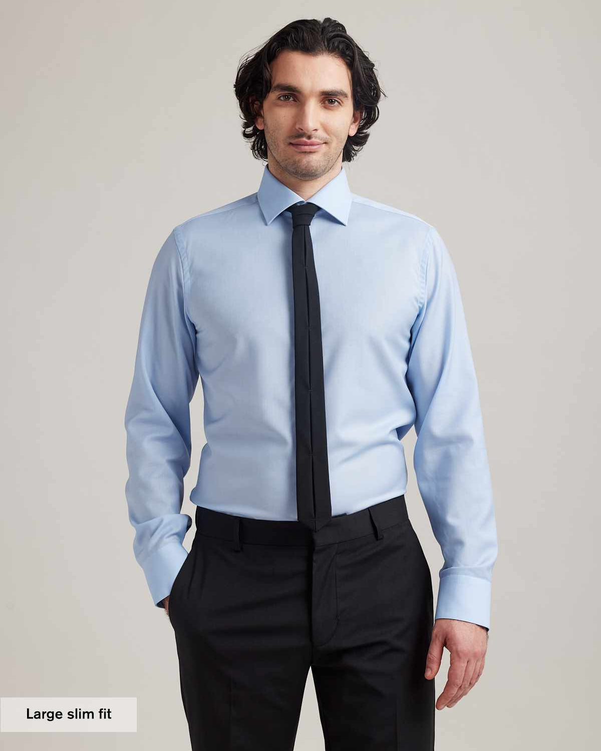 Man wearing a light blue merino wool business shirt with english spread collar and black tie in slim fit