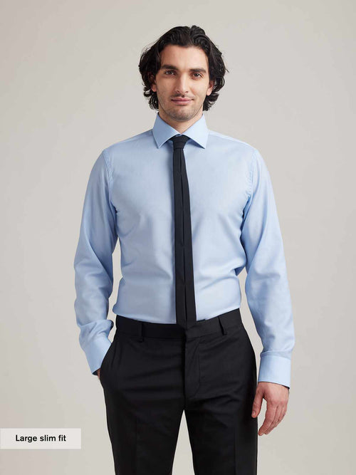 Man wearing a light blue merino wool business shirt with english spread collar and black tie in slim fit