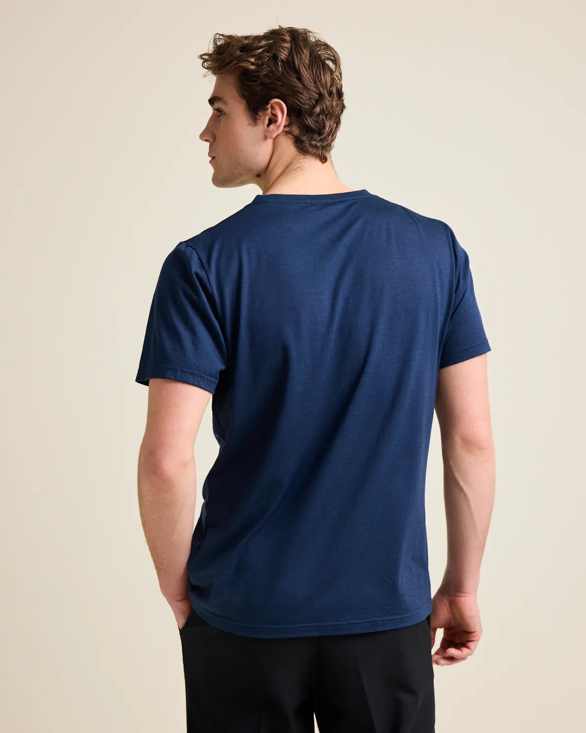 back view of a man wearing a navy T-shirt on a white background