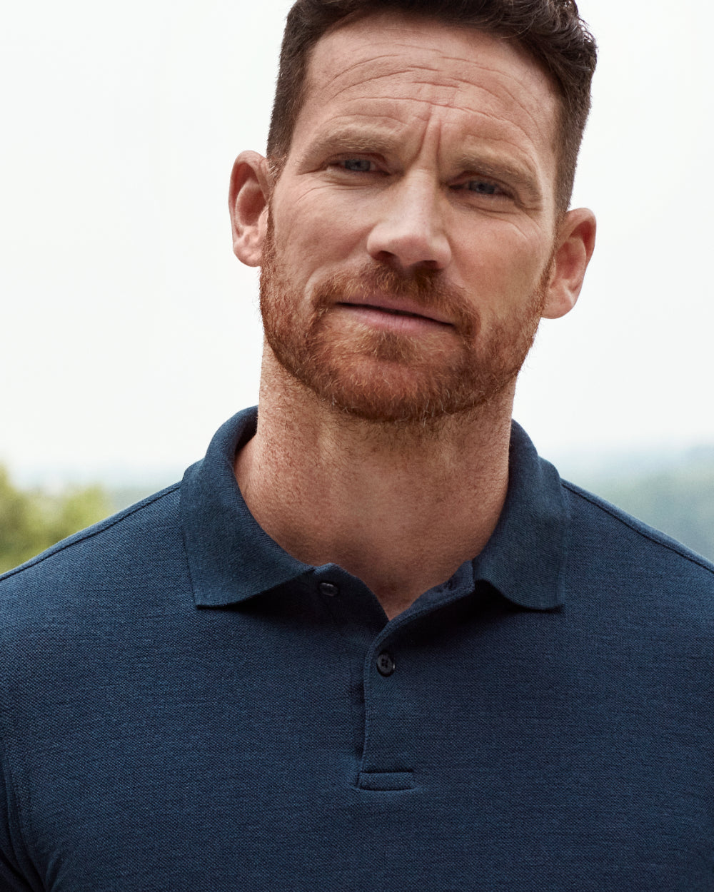 Close up of man wearing a merino wool polo in navy blue color with rub collar and corozo buttons