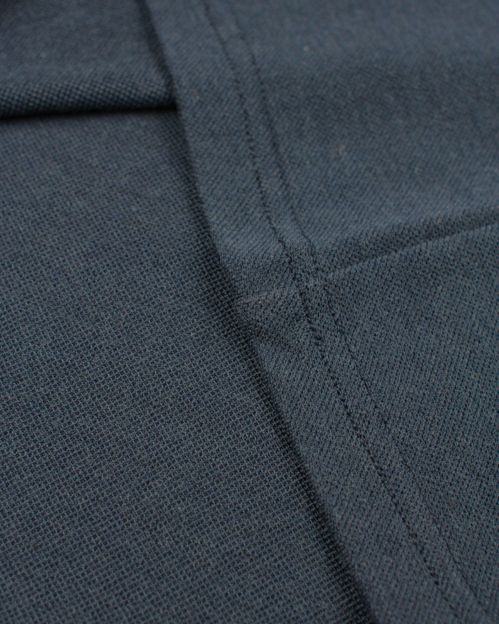 detail of pique fabric on navy polo made of merino wool
