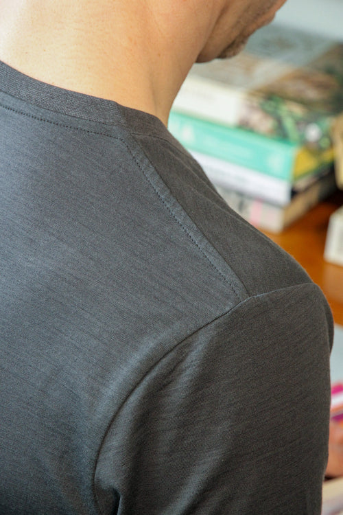 Close-up of the shoulder seam on a men's dark grey merino wool T-shirt by Wolk, designed for durability and style.