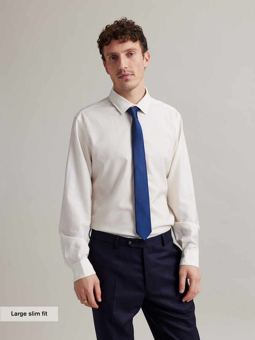 Man wears a white merino formal shirt with navy tie