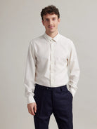 Front view of a man wearing a white merino wool dress shirt on a navy trousers.