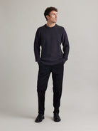 Man wears a dark grey merino wool sweater in rice knit with round collar and heavy weight warm jumper