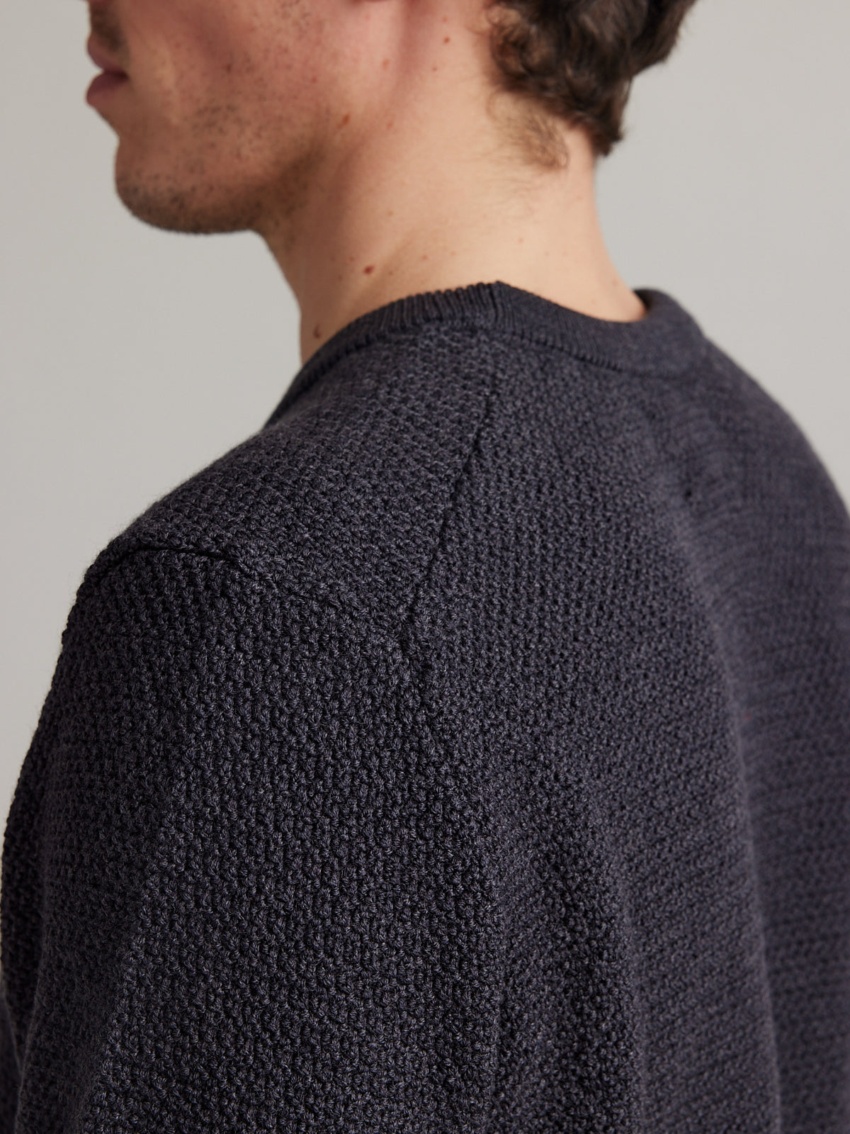 backside seam of merino wool sweater in rice knit structure and anthracite dark grey color