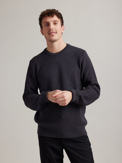 Man wearing a merino wool sweater in anthracite dark grey in rice knit stitch