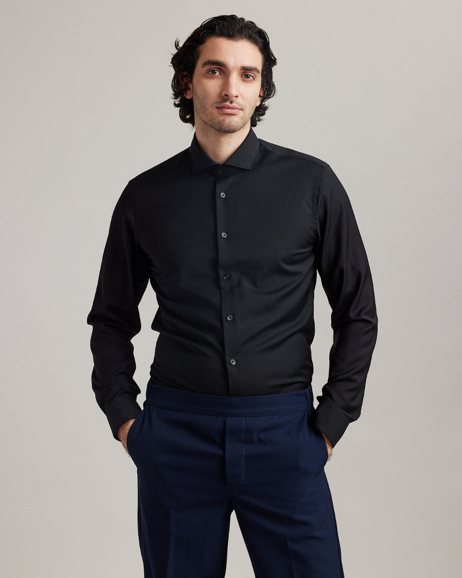 Man wears black merino wool formal shirt with spread collar and long sleeves in slim fit