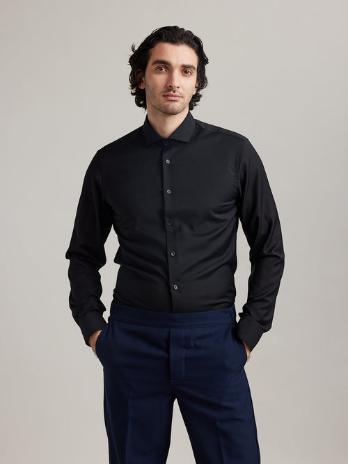 Man wears black merino wool formal shirt with spread collar and long sleeves in slim fit