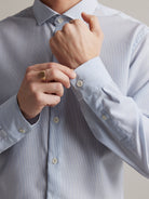 cuff detail of merino shirt in light blue stripe and white corozo buttons